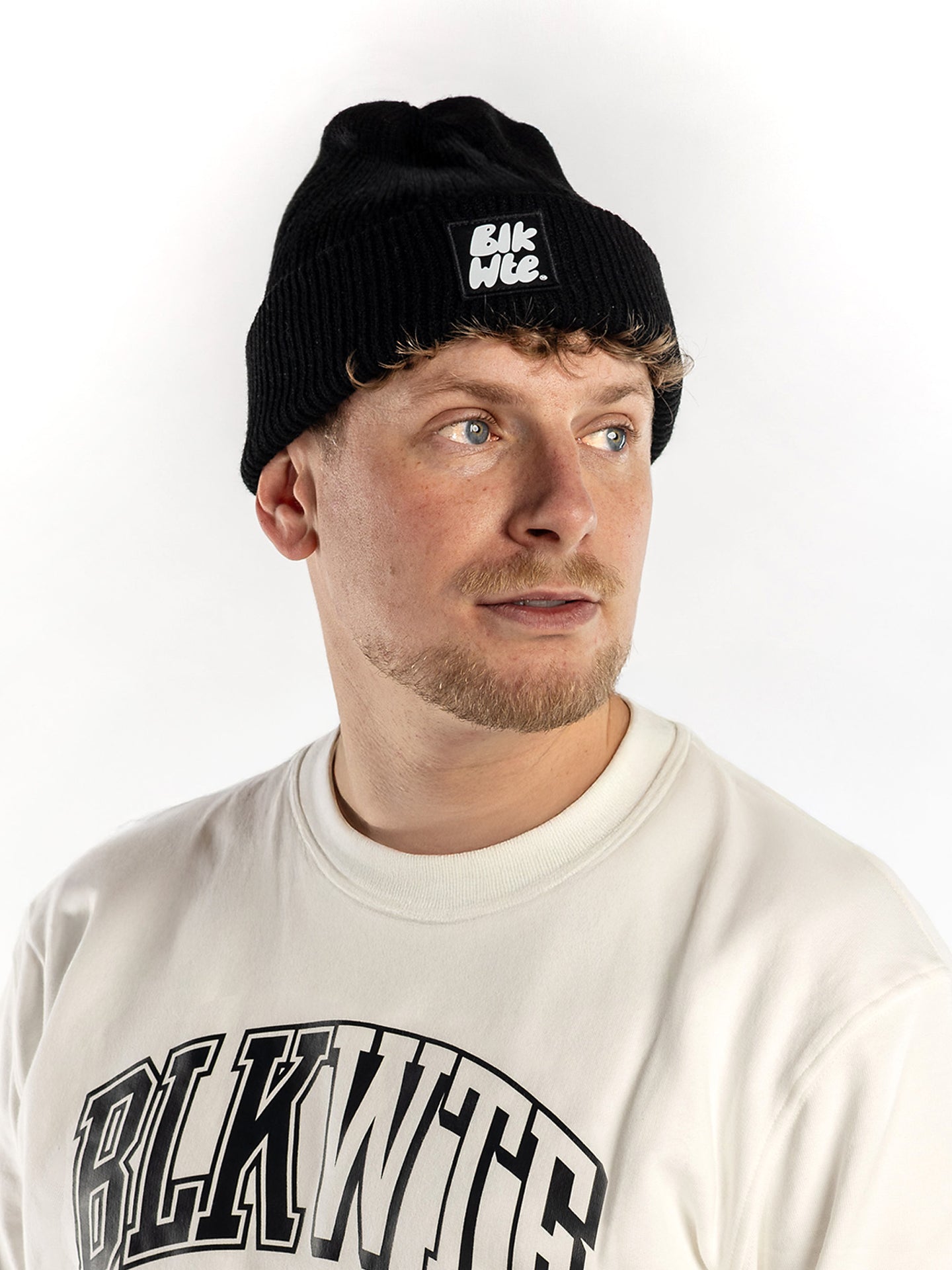 Person wearing a black beanie and white sweatshirt with 'BLK WTE' branding on a white background
