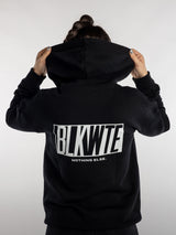 Female wearing a black hoodie with 'BLKWTE' branding on the back against a white background
