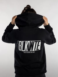 Female wearing a black hoodie with 'BLKWTE' branding on the back against a white background