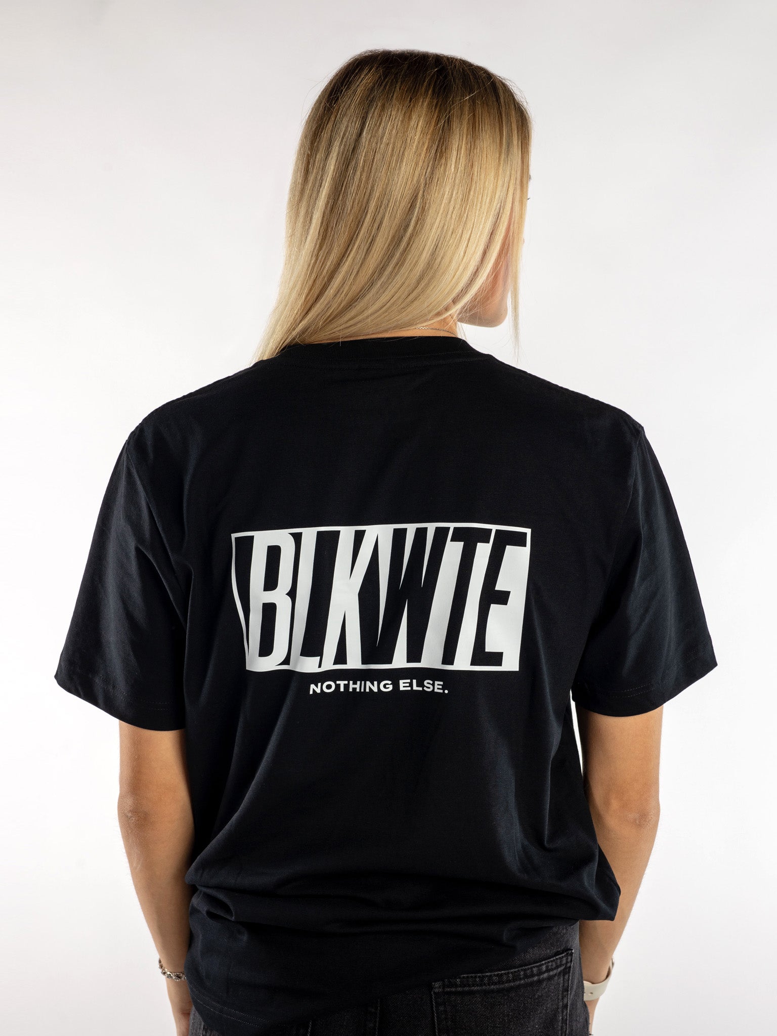 Female model in a Black t-shirt with BLKWTE logo across the back in white 