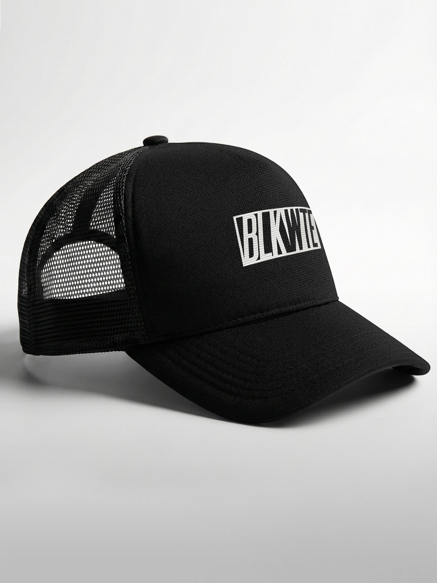 Black trucker cap with 'BLKWTE' logo on the front panel on a light gray background